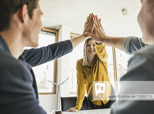 Happy business team high fiving in office
