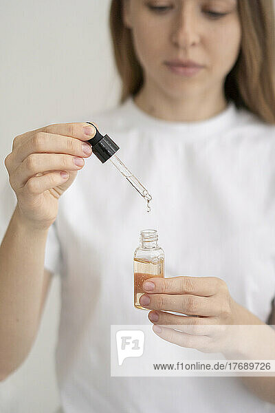 Junge Frau gießt Tropfen in eine Flasche ätherisches Öl