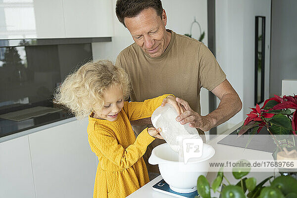 Smiling father and daughter baking together in kitchen at home