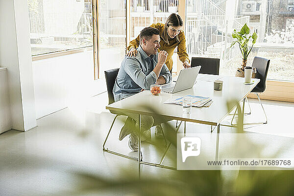Businesswoman and businessman with laptop at desk in office