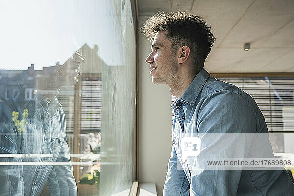 Young businessman looking out of window in office