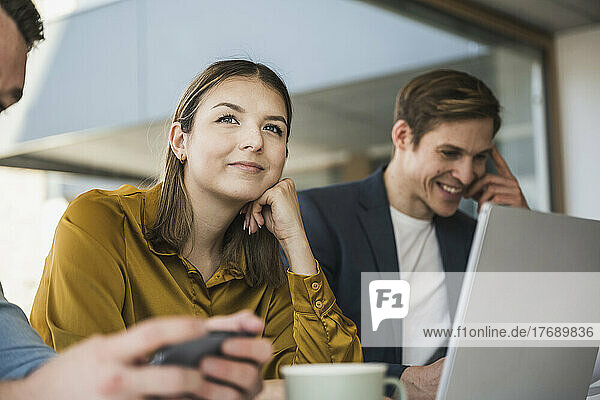 Businesswoman with colleagues daydreaming in office