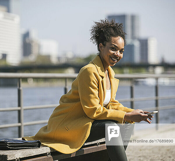 Happy businesswoman with smart phone on bench