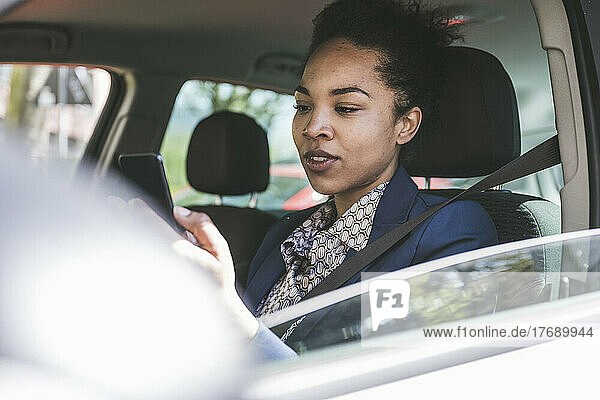 Young businesswoman using smart phone sitting in car