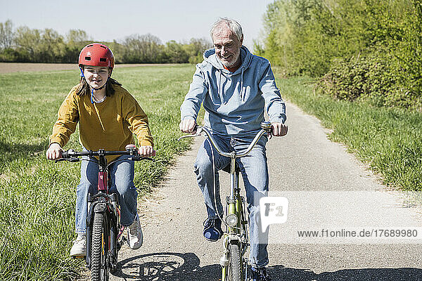Großvater und Enkelin radeln auf Fußweg
