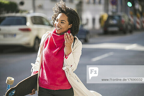 Businesswoman laughing and sending voicemail over mobile phone on street