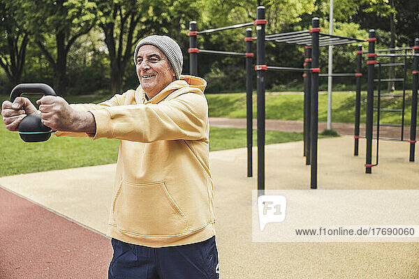 Happy senior man exercising with kettlebell at park