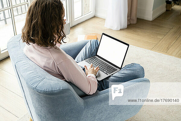 Junge Geschäftsfrau tippt auf dem Laptop und arbeitet zu Hause