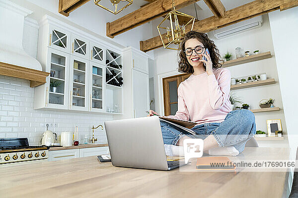 Happy woman talking on smart phone at home