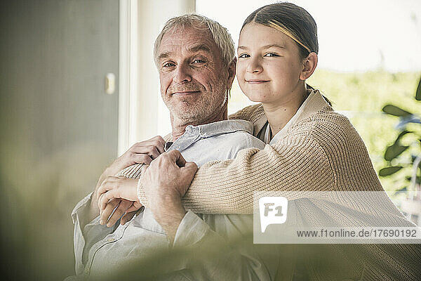 Glückliche Enkelin umarmt Großvater zu Hause