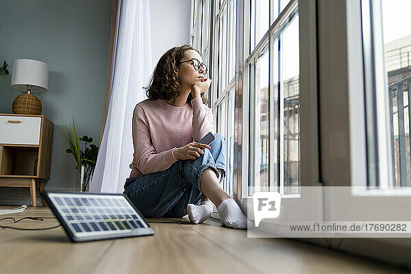Contemplative freelancer looking through window in living room