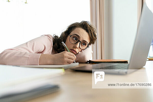 Müde Frau benutzt Laptop und lernt zu Hause