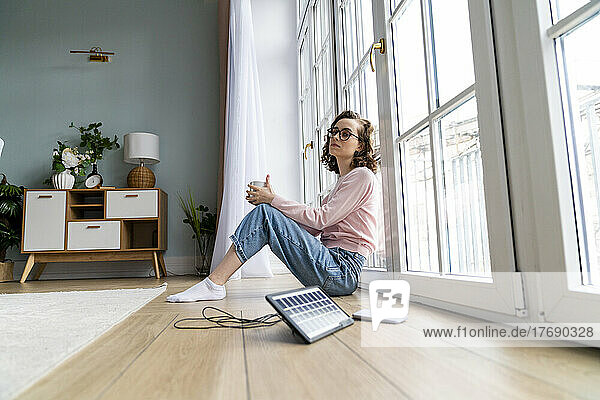 Contemplative businesswoman leaning on window at home