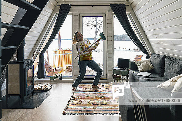 Glückliche Frau tanzt zu Hause mit Besen