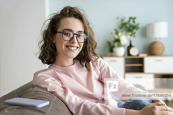 Glückliche Frau mit Brille im heimischen Wohnzimmer