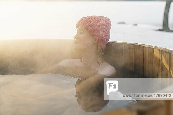 Topless woman in knit hat taking hot water bath in winter