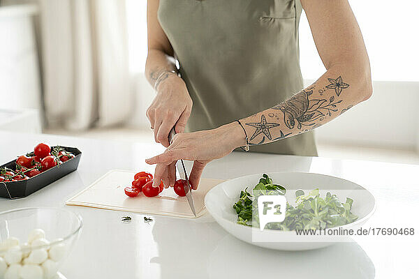 Woman cutting tomato on kitchen island at home