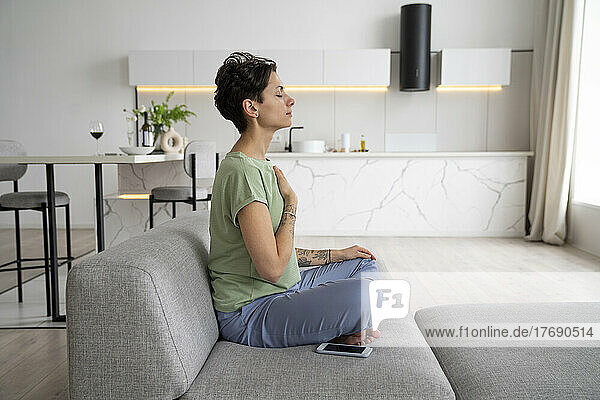 Woman doing relaxation exercise sitting on sofa at home