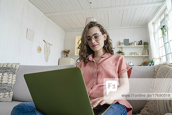 Young businesswoman wearing eyeglasses working on laptop at home