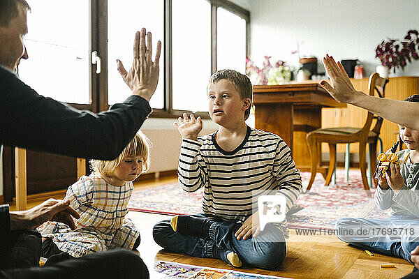 Eltern  die mit ihrem Sohn  der das Down-Syndrom hat  im Wohnzimmer zu Hause sitzen  High-Five machen