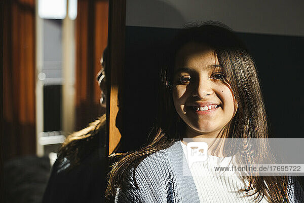 Portrait of happy girl with sunlight on face at home