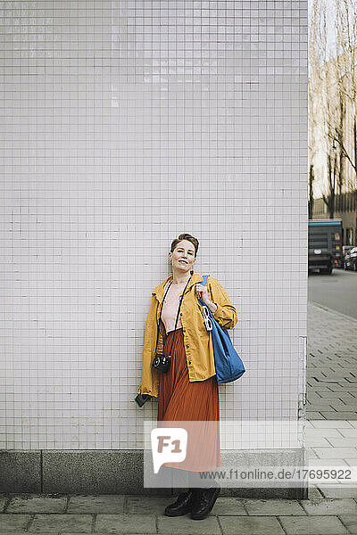 Porträt einer mittleren erwachsenen Frau mit Tasche und Kamera auf einem Fußweg