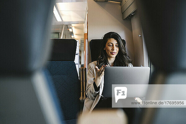 Geschäftsfrau  die im Zug sitzend einen Videogespräch über einen Laptop führt