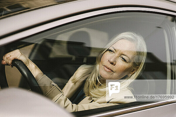 Blonde Geschäftsfrau schaut durch ein Autofenster