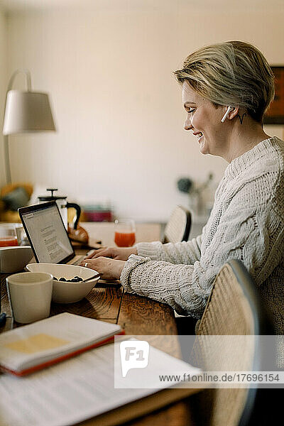 Side view of lesbian businesswoman using laptop sitting at dining table
