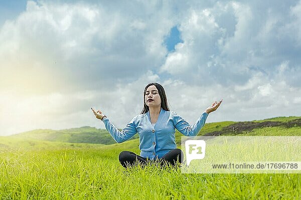 Mädchen sitzt und macht Meditation Yoga auf dem Feld  Frau macht Yoga im Freien  junge Frau macht Yoga auf dem Gras auf dem Feld mit blauem Himmel im Hintergrund