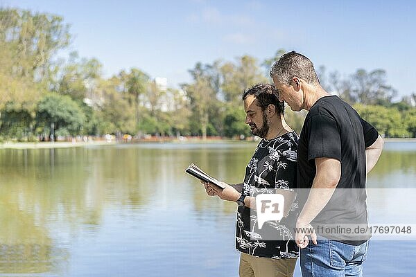 Couple of mature men reading in a lake  with a happy and relaxed attitude