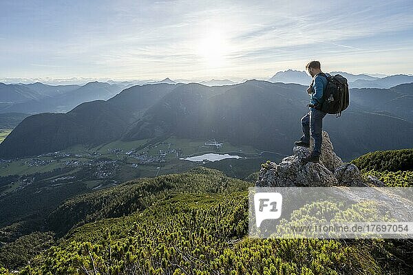 Wanderer steht auf einem Felsen zwischen Latschenkiefern  Blick auf Berglandschaft mit Pillersee  Abstieg vom Heimkehrerkreuz  Nuaracher Höhenweg  Loferer Steinberge  Tirol  Österreich  Europa