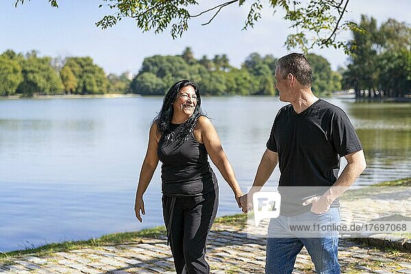 Multiethnisches Paar  bestehend aus einer Andenfrau und einem kaukasischen Mann  die an einem See spazieren gehen. Glückliche Ausdrücke und Gesichter von Liebenden