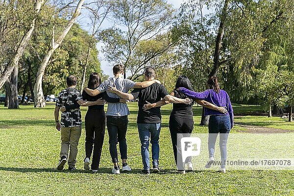 Multiethnische Familiengruppe  die Arm in Arm in einem Park spazieren geht. Familie  Gruppe  Teamarbeit  Freundschaft Konzept
