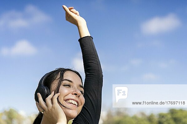 Young woman listening to music outdoors with headphones. Expression of happiness  winning attitude. Copy space