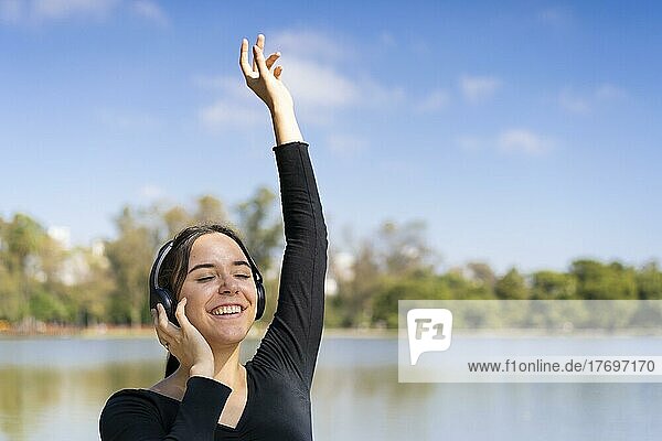 Junge Frau  die im Freien mit Kopfhörern Musik hört. Ausdruck von Glück  gewinnende Einstellung. Textfreiraum