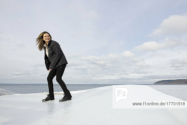 Young woman balancing on ice by sea