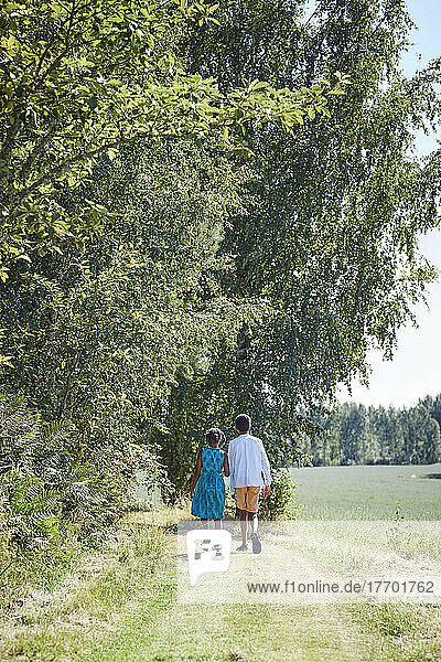 Siblings walking on path in forest