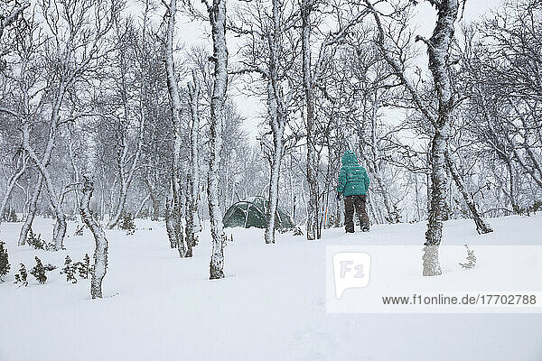 Woman camping in snowy forest