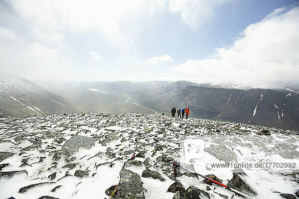 People walking through snow and rocks on mountain