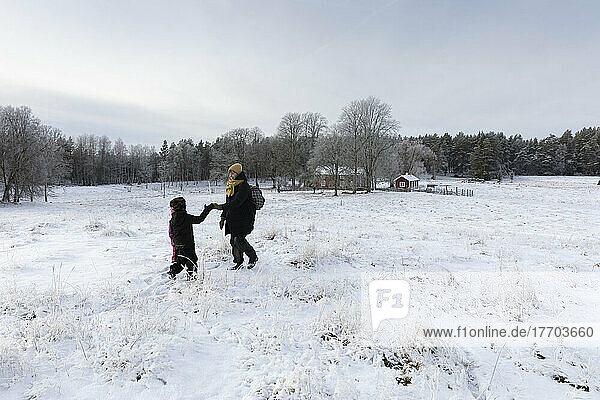 Mother and son holding hands in snowy field