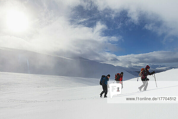 Drei Wanderer auf einem verschneiten Winterspaziergang beim Aufstieg zum Geal Charn  in der Nähe von Laggan; Schottland