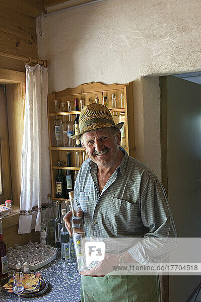 Der Besitzer des Bauernhofs und Gasthauses Lammerbichlalm auf der Lammerbuhelalm mit einer Flasche seines selbstgebrannten Schnapses. Lammerbuhealm. Kitzbühel. Österreich