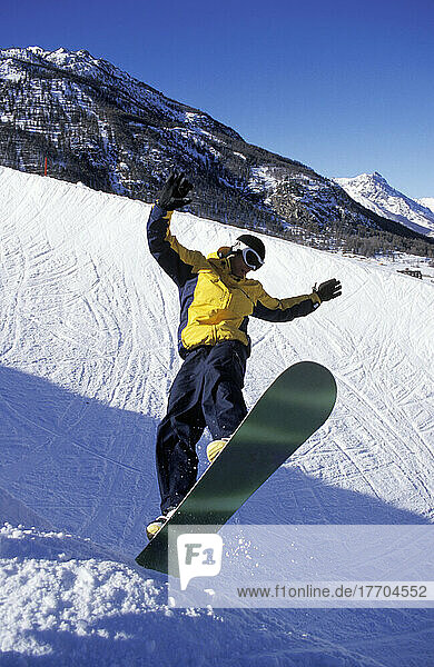 Mann springt auf Snowboard in den Alpen