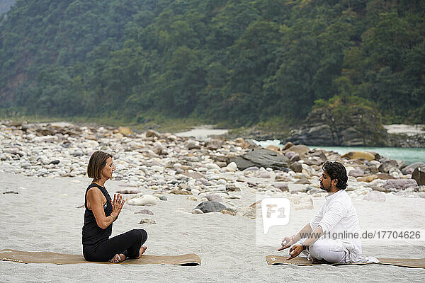 Yoga Class on the bank of the River Ganges flowing through the Foothills of the Himalayas between Rishikesh and Devprayag in the Ganges Valley  Uttarakhand  India; Rishikesh  Uttarakhand  India