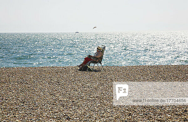 Sitzen auf einem Strandstuhl am Rande des Wassers; Seaford  East Sussex  England