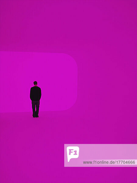 Silhouette eines Mannes  der vor einem hellrosa Hintergrund steht; London  England