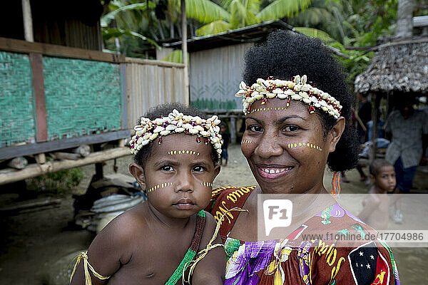 Mutter und Kind mit Muschel-Stirnbändern am Ufer des Dorfes Siboma  Insel Lababia  Huon-Golf  Provinz Morobe  Papua-Neuguinea; Dorf Siboma  Provinz Morobe  Papua-Neuguinea