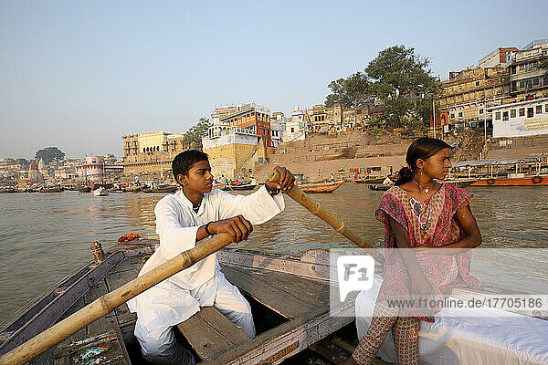 A Couple Rowing A Boat In The River Ganges Past The Bathing Ghats; Varanasi  India