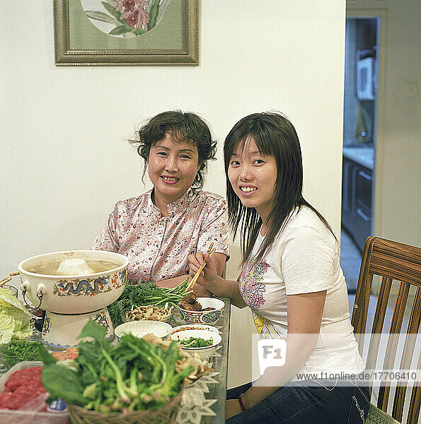 Eine Mutter und ihre Tochter teilen sich ein traditionelles chinesisches Eintopfgericht mit Fleisch  Blattgemüse und Pilzen. Peking  China.